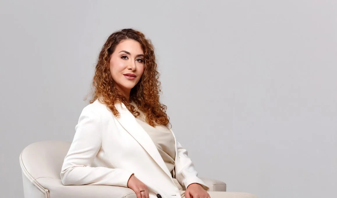 Dra. Ana Paula Naspolini, dermatologista, sentada em uma poltrona olhando para a câmera